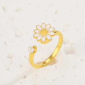 Detail of a rotating daisy ring with a lustrous white pearl on a gold-tone band