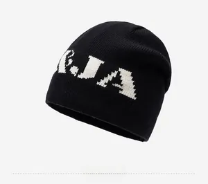 Detail of black knitted beanie featuring white KJA jacquard lettering and warm fabric texture