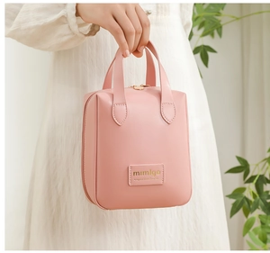 Detail of soft pink PU leather makeup bag with gold zipper and durable handle grip