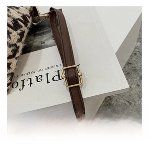 Gros plan sur la bandoulière en cuir marron ajustable avec boucle dorée du sac à main