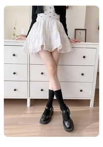 Detail of black cotton calf socks styled with a white layered lace skirt and Mary Janes