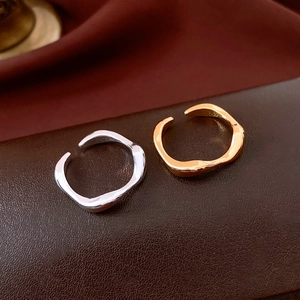 Detailed view of wave-shaped 18k gold and silver rings on leather and silk background