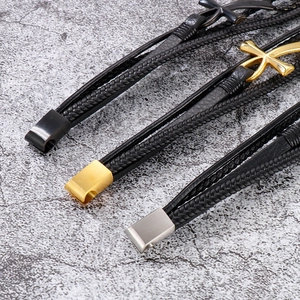 Detail view of woven leather bracelets with gold, silver, and black Ankh cross charms