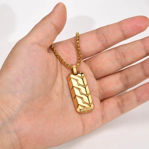 Detailed close-up of golden stainless steel necklace with geometric tire pattern pendant
