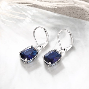 Detail of blue cushion cut earrings on marble with leverback silver setting