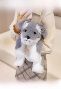 Detailed view of grey and white plush schnauzer toy held in a cozy home setting