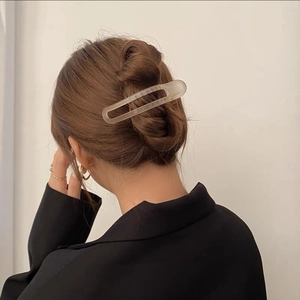 Close-up of matte geometric oval hair claw clip securing a bun on a woman in a black suit