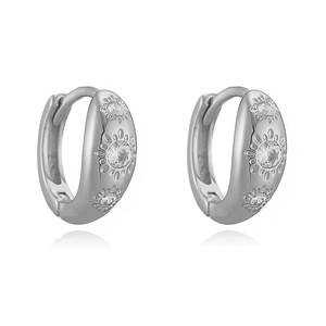 Détails rapprochés des boucles d'oreilles argentées avec gravures soleil et zircons cubiques