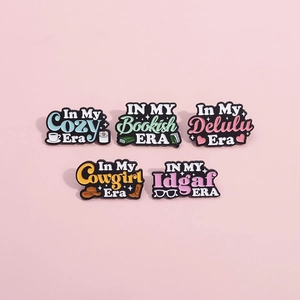 Set of five colorful enamel pins with inspirational era-themed quotes on a pink background