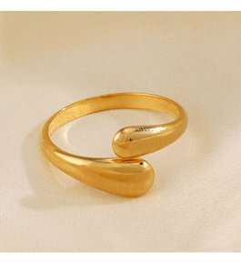 Macro shot of minimalist gold drop-shaped open ring detail on beige fabric texture