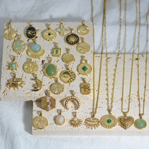 Retro gold pendants with sun and moon motifs and natural stones on marble slabs