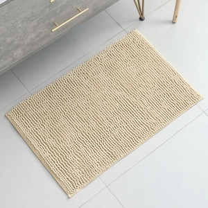 Detailed texture of beige chenille bath mat showing soft absorbent loops on tile floor