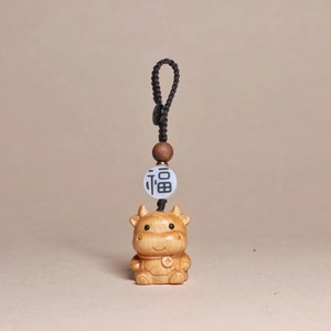 Detailed view of hand-carved wooden ox pendant with woven cord and lucky bead