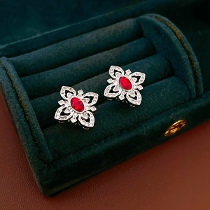 Detailed view of silver flower earrings with red zircon in a green velvet jewelry box