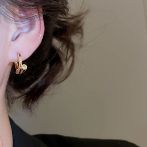 Gros plan d'une boucle d'oreille clou en plaqué or 18k avec petit zircon sur une oreille
