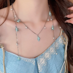 Détail d'un collier bohème multi-rangs avec étoile de mer bleue, conque et perles sur modèle