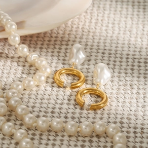 Boucles d'oreilles en acier doré en forme de C avec perles baroques blanches sur tissu