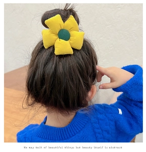 Detailed back view of a yellow sunflower hair scrunchie on a child's bun hairstyle