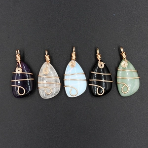 Detail of five wire-wrapped crystal pendants in various colors with golden metal coils
