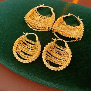 Macro shot of gold plated chain fringe hoop earrings with zircons on green velvet
