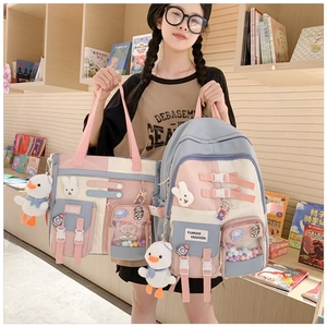 Close-up of pastel pink and blue school backpack with cute cartoon pendants and badges