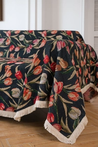 Detail of floral jacquard sofa throw with red tulip patterns and creamy white fringe