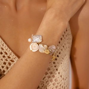 Detail of beach style necklace featuring seashell, starfish, and mother of pearl elements