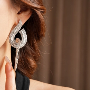 Close-up of model wearing large silver drop earrings with inlaid crystals and tassels