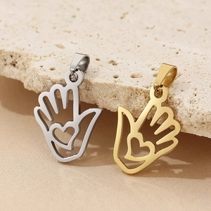 Detail of hollow hand heart charms in gold and silver finish on textured stone