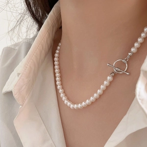 Detail of elegant pearl choker necklace with a silver OT clasp on female model
