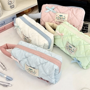 Flat lay of quilted pencil cases in pink, white, mint, and blue with bow ribbon details