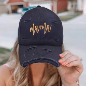 Close-up of golden Mama embroidery on a black distressed vintage baseball cap