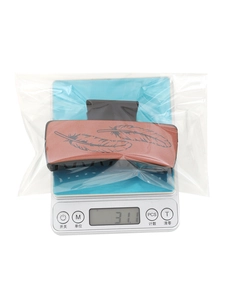 Brown western faux leather hair claw clip with feather pattern on a digital scale weighing 31.1g