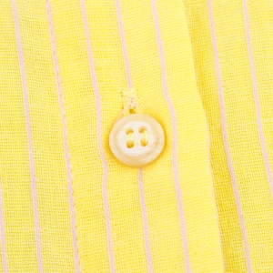 Dettaglio di tessuto a righe giallo limone con linee rosa e un bottone a quattro fori