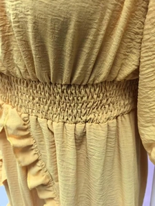 Detail of yellow summer dress featuring smocked waist and textured pleated fabric