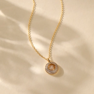 Detail of a gold plated round pendant necklace with sparkling pavé cubic zirconia
