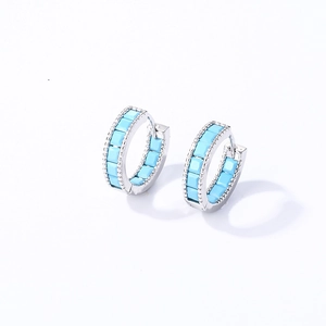 Detail of silver hoop earrings with sky blue square stones and beaded edge craft