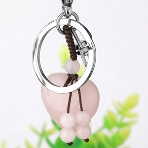 Handmade rose quartz heart keychain with brown woven tassel and pink beads on white background