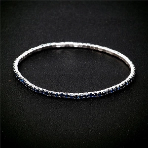 Macro shot of a 2.0mm silver bracelet with vibrant blue crystals on black background