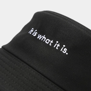 Chapeau bob en coton noir minimaliste avec broderie blanche texte It is what it is.
