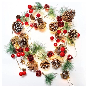Close-up of Christmas garland with pine cones, red berries, bells and warm LED copper lights