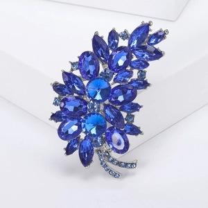 Macro shot of silver alloy flower brooch with navy blue rhinestones and crystal details