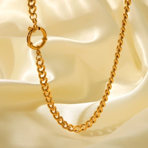 Detailed view of 18K gold plated Cuban chain necklace with round clasp on satin fabric