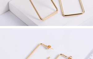 Macro shot of rectangular gold titanium earrings showing polished finish and stud backing