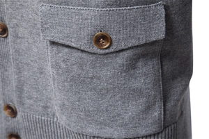 Close-up of gray knit cardigan fabric featuring brown amber buttons and pocket detail