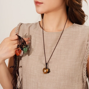 Close-up of heart-shaped natural stone pendants on woven cords worn by a model
