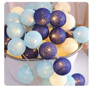 Close-up of blue and white cotton ball string lights with warm glowing fiber textures