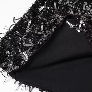 Detail of black mini dress with dense silver sequins and elegant tassel fringe embellishment