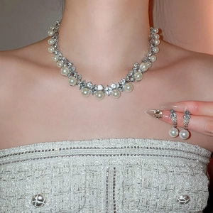 Elegant silver jewelry set with pearls and diamonds shown on a model in tweed outfit