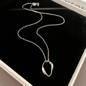 Detail of a minimalist silver chain necklace with an irregular geometric ring pendant